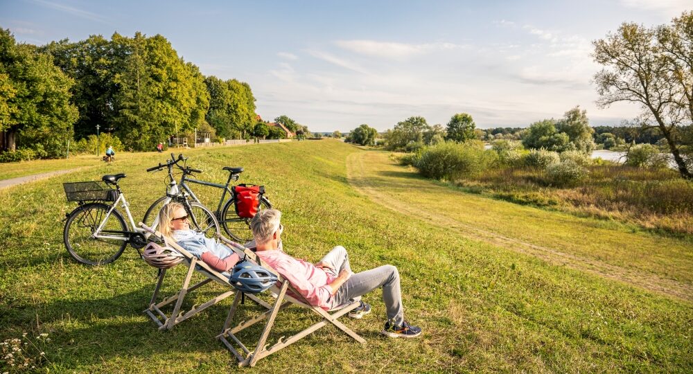 Pärchen auf Liegen am Deich mit Fahrrädern an der Elbe